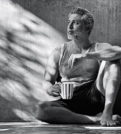 A man sitting with a cup of coffee, looking down.