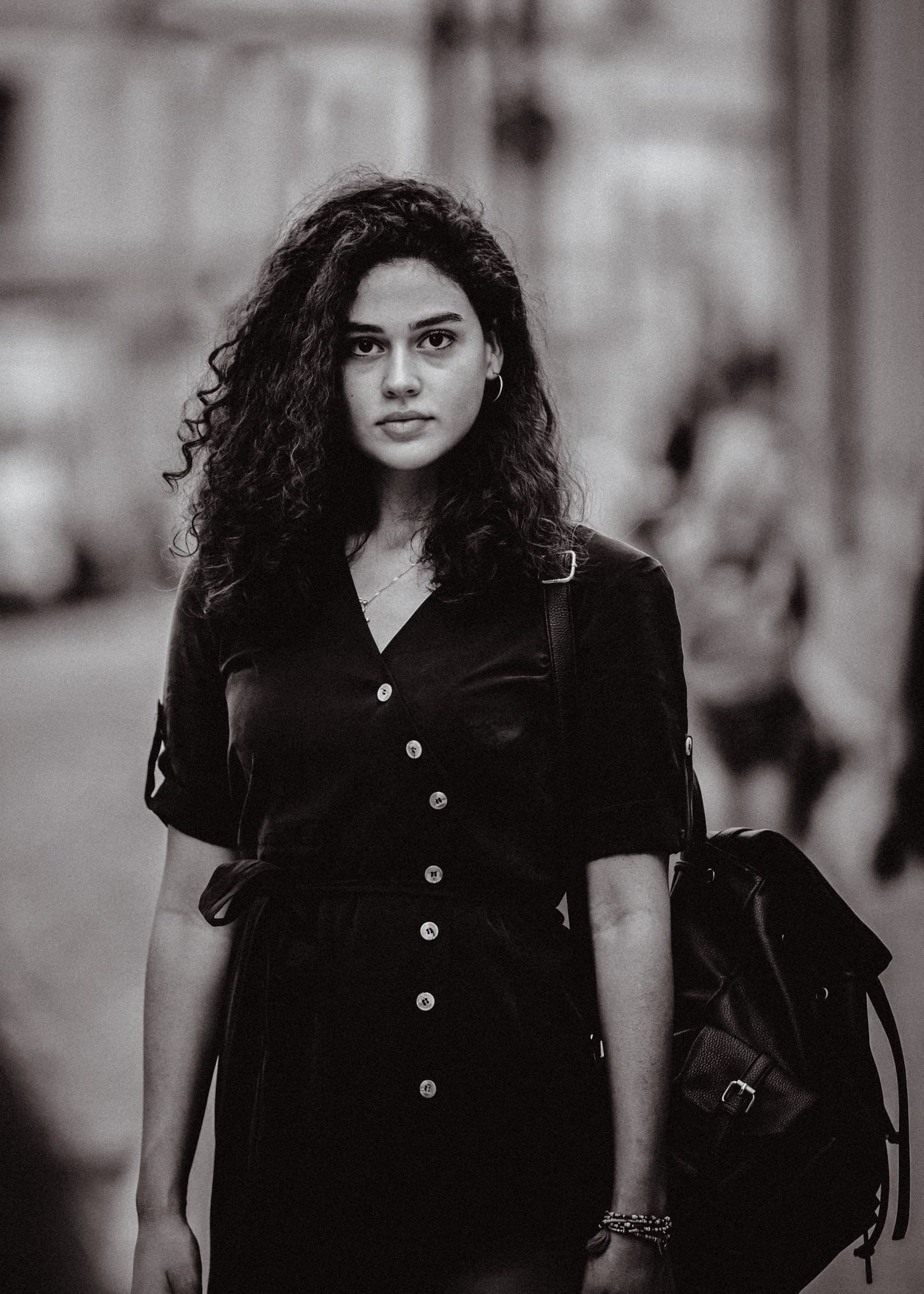 A woman in a light coat walking away on a city sidewalk.