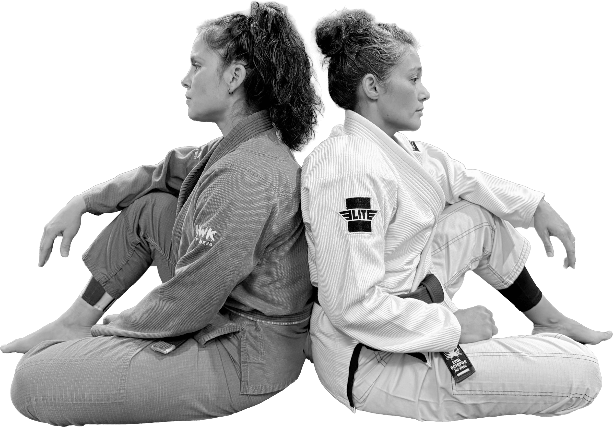 Two women in gis sitting back to back on a mat, shown in profile.